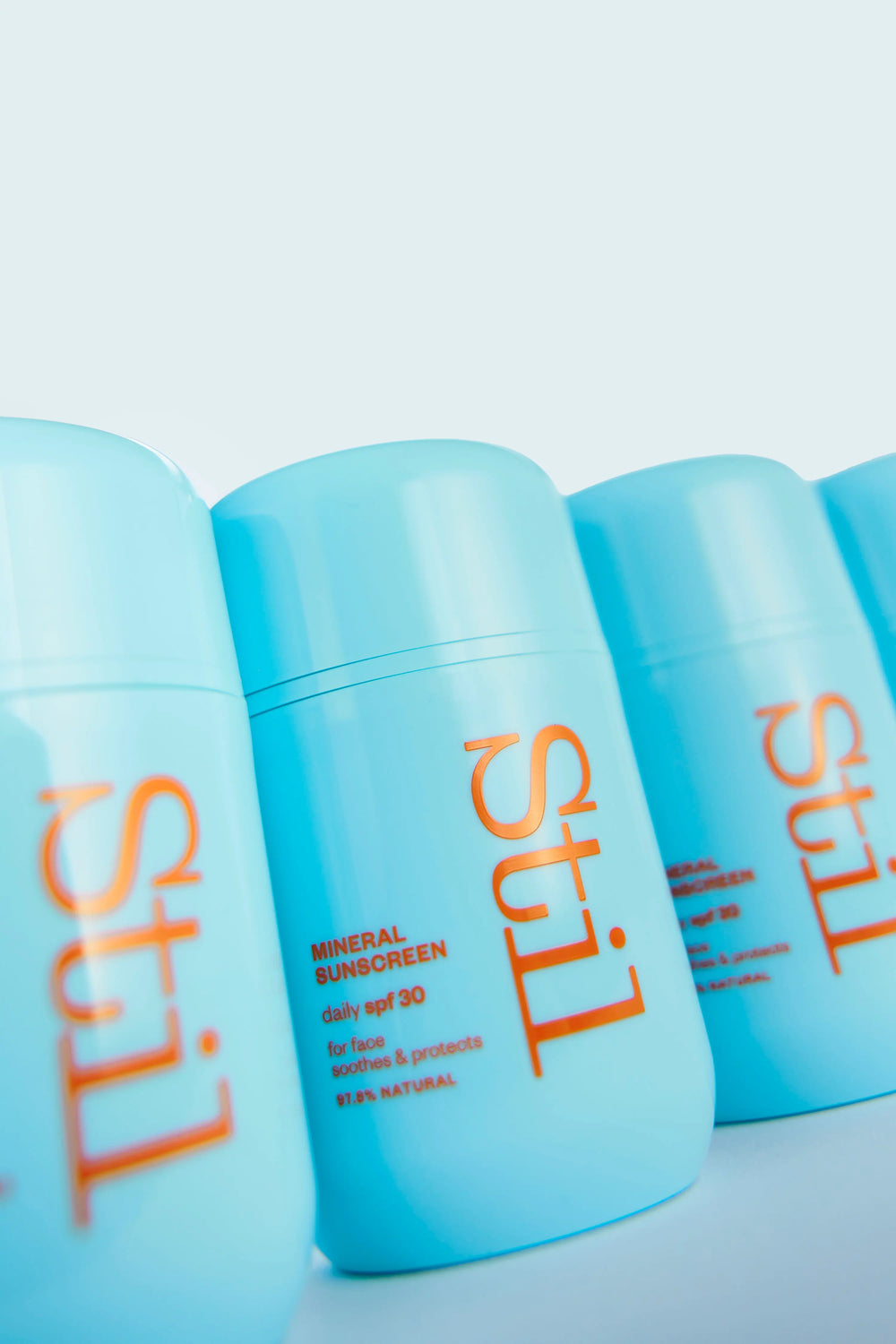 Row of blue sunscreen bottles with 'Stil' branding on a light blue background