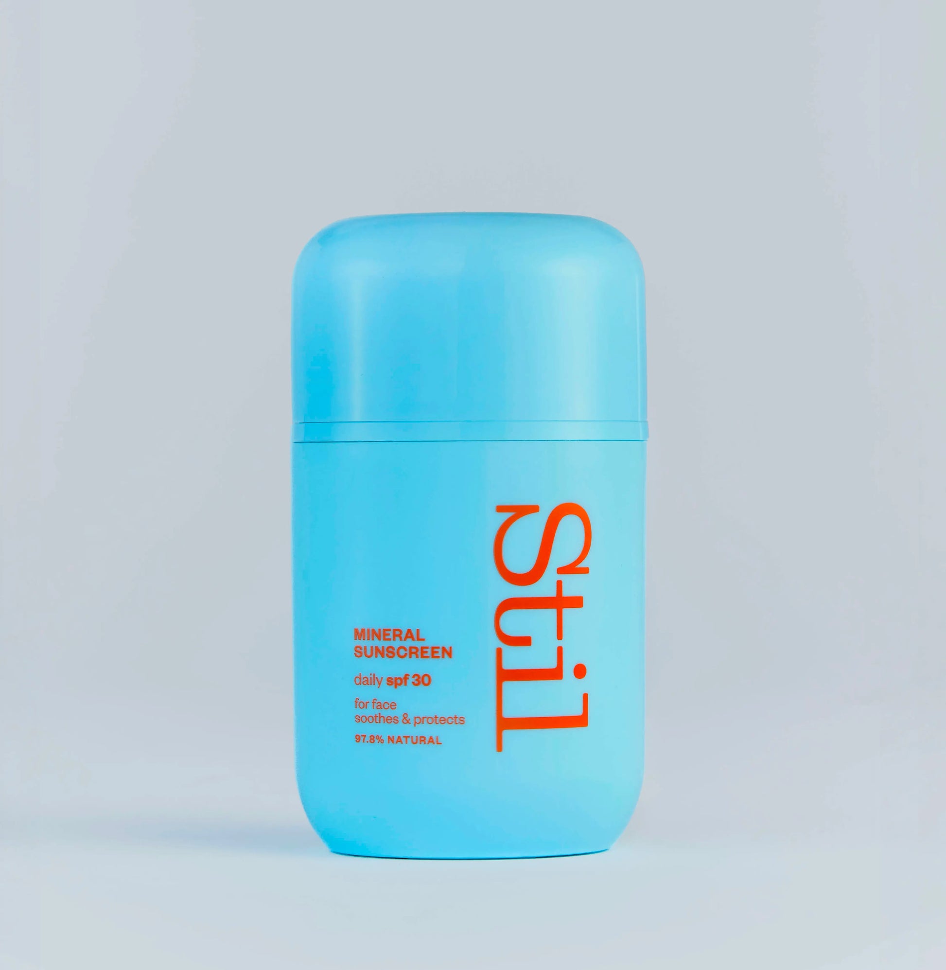 Blue sunscreen bottle with 'stil' branding on a light gray background