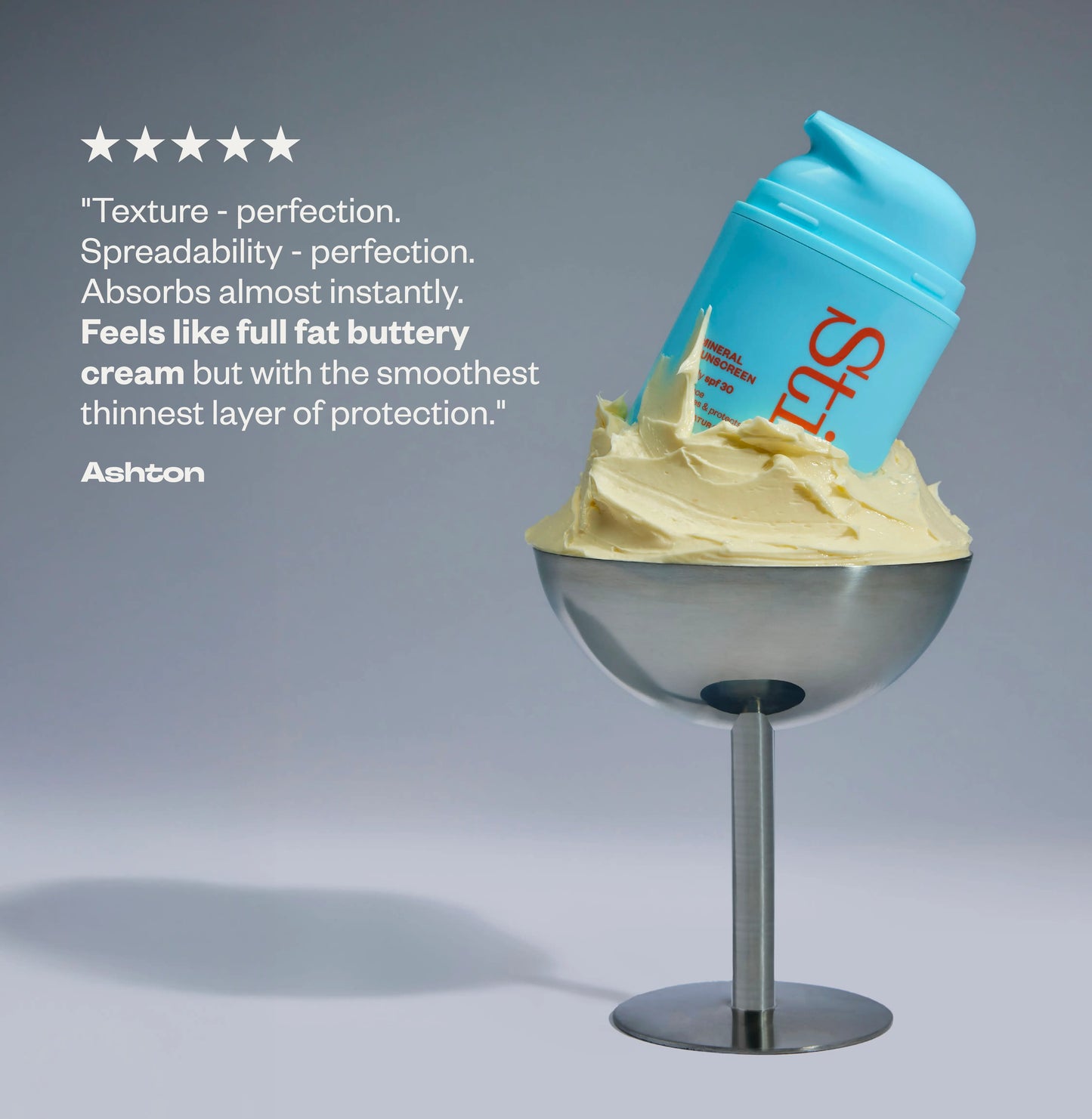 Stil bottle in cream on a stand against a gray background