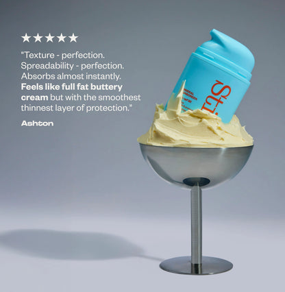 Stil bottle in cream on a stand against a gray background